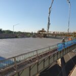 This image captures a bridge deck concrete pouring operation in progress during daytime.