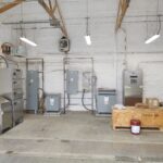 This image appears to show an industrial or utility facility, related to water treatment or electrical distribution. The equipment includes control panels, electrical cabinets, and a transformer.