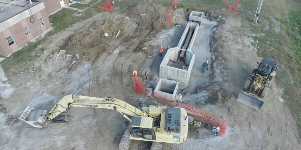 This image shows an active construction site with heavy machinery, including a Komatsu excavator and a front-end loader, working near a building.