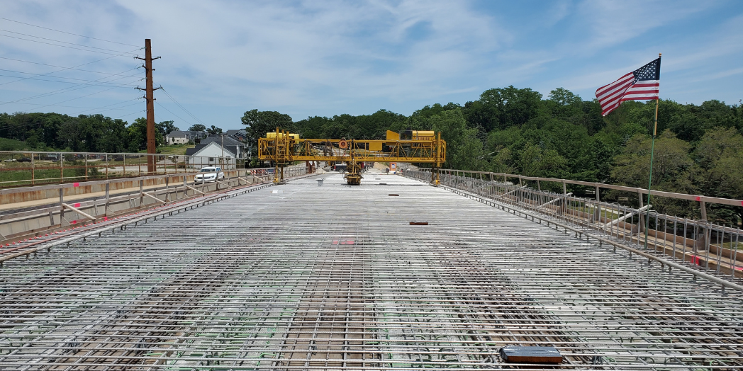 Steel reinforcement covers the Plainfield Road bridge deck before concrete placement, with yellow construction equipment spanning the deck.