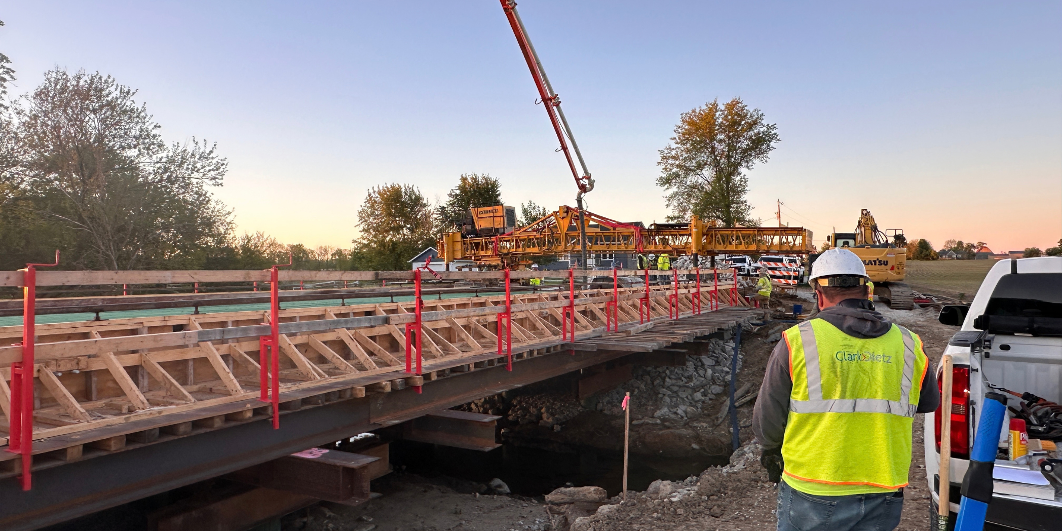 A Clark Dietz inspector observes Bridge No. 109 deck construction, with wooden forms, temporary steel supports, and a concrete pump overhead.