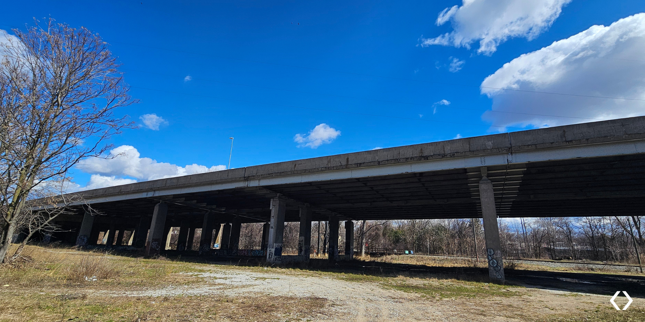 Side view of the completed US-131 bridge rehabilitation in Grand Rapids, showing steel girders and concrete piers above railroad tracks.